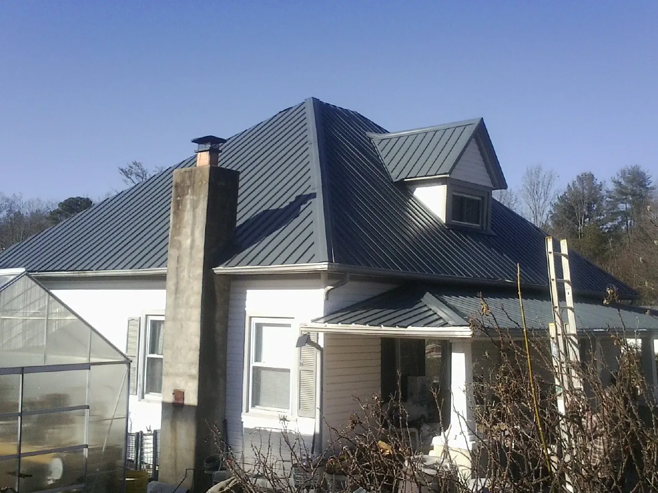 Dark blue standing seam metal roof on a white farmhouse with dormer — Slate & Tile Roof Repair by Roofing Brothers in Montesano