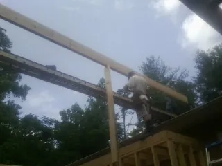 Carpenter setting a ridge beam over a new addition frame — Ice Dam Removal by Roofing Brothers in Montesano