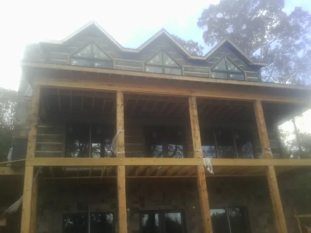 Dormers and porch framing on a large log home under construction — Roof Coating work by our crew in Montesano
