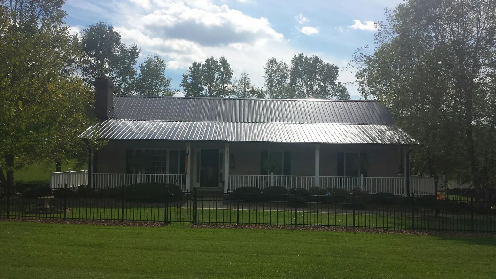 Gray metal roof on a brick ranch with a full width front porch — Gutter Guard Installation work by our crew in Montesano