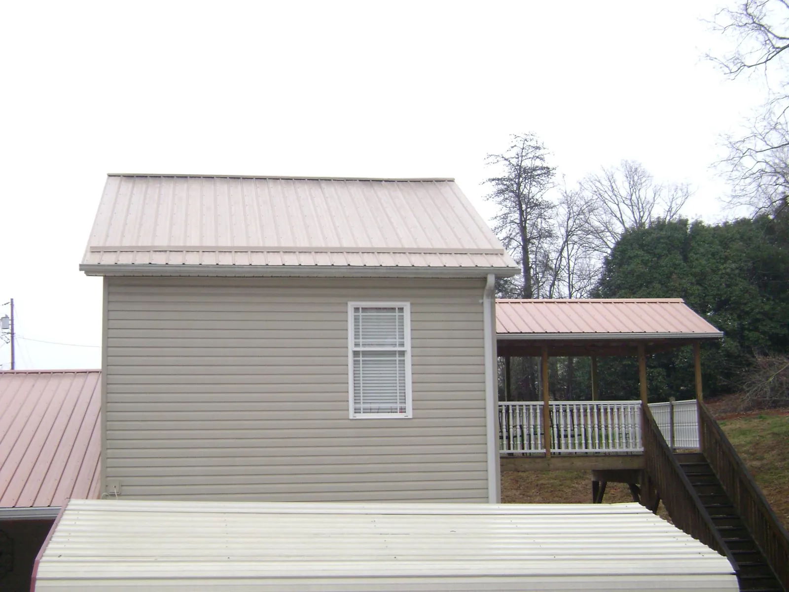 Tan metal roofs on a two story addition and attached porch, from a Roof Replacement job in Montesano