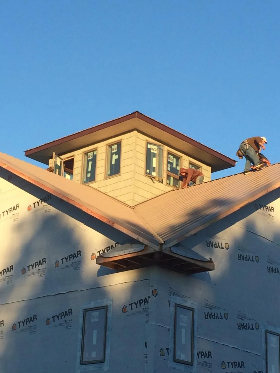 Roofers working around a rooftop cupola on a new metal roof at sunset — Roof Waterproofing in Montesano by Roofing Brothers